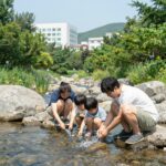 가평 아침고요수목원 계곡 카페 여름 나들이 아침고요수목원 계곡에서 발을 담그고 쉬는 가족의 모습, 시원한 물과 녹음이 어우러진 여름 풍경