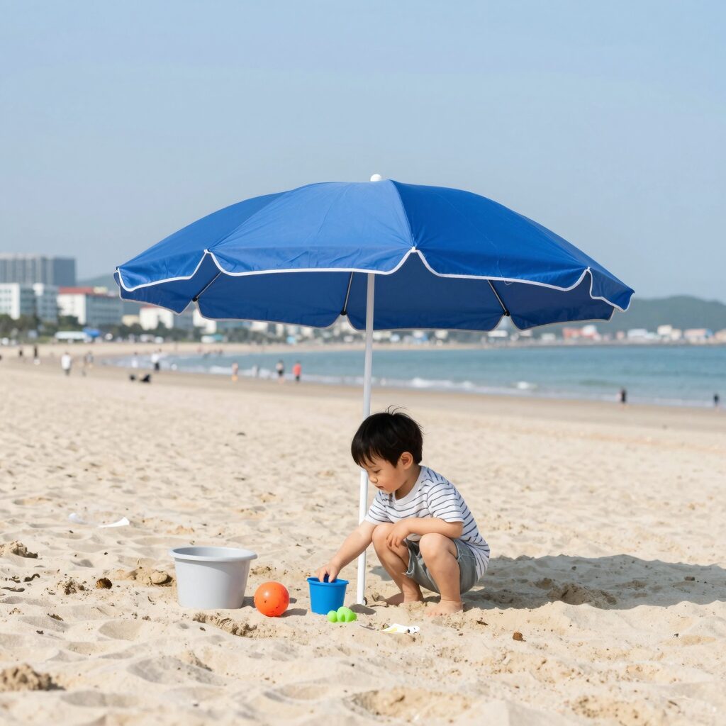 해변에 설치된 유아 파라솔 세트 아래 아이가 장난감을 가지고 노는 모습