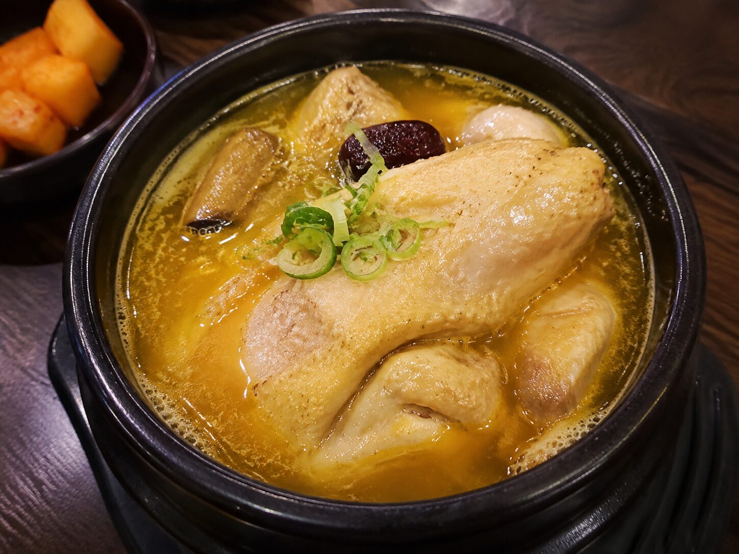 정관 백세상황버섯삼계탕의 진한 노란색 상황버섯 삼계탕 국물과 닭고기