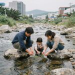계곡에서 다슬기를 잡고 있는 가족의 모습. 맑은 물속에 돌 틈 사이로 다슬기가 보인다.