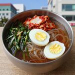 열무 물냉면 만들기 시원한 여름 한 그릇 시원한 열무 물냉면이 그릇에 담겨 있고, 위에 열무김치와 오이채, 반숙 계란, 깨가 뿌려져 있다.